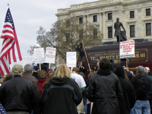 Tea Party protestors carrying pickets and an American flag.