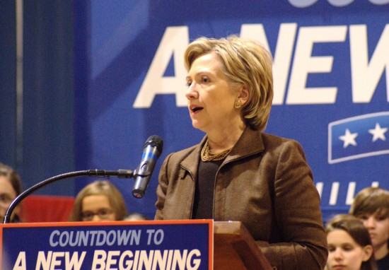Then-presidential candidate Hillary Clinton is shown standing behind a podium with a placard stating: Countdown to a New Beginning. A number of children are shown in the background.