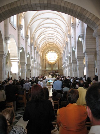 Numerous people are shown from behind standing in a church.