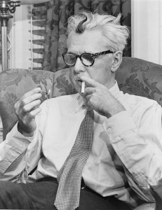 Black and white photo of Thurber, who is seated in a wing chair looking at a lit match he holds in one hand; his other hand holds a cigarette to his lips.  He has unkempt white hair with a dark streak in the center of his forehead.  He wears dark patterned glasses, a white button-up shirt and a tie.