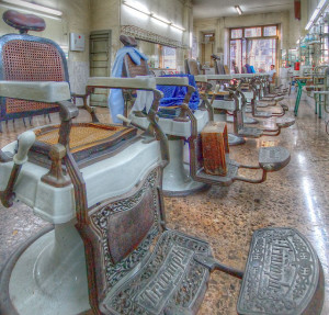 Photo of the interior of an antique barber shop, showing a line of antique barber chairs facing a mirrored wall