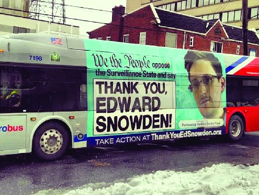 An ad on the side of a bus featuring a photo of Edward Snowden. The text says 