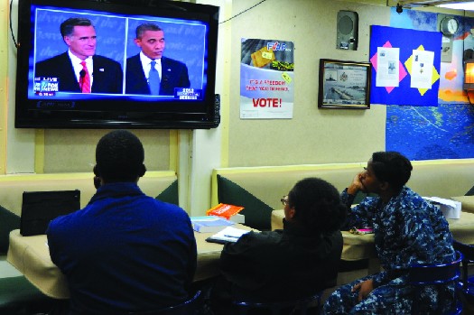 An image of three people watching a television. On the television screen are Mitt Romney and Barack Obama.