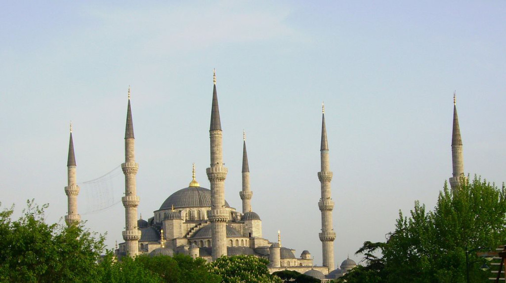 The mosque has a central dome topped with a golden steeple. It is in the center of several other domes varying in size and elevation. All the domes are blue, but the stone of the building is grey. There are six towers (minarets) framing the mosque; each topped with a point made of the same blue stone.