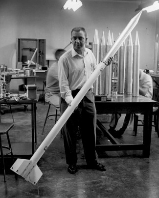 Photograph of James Van Allen holding a small rocket, which was part of a 