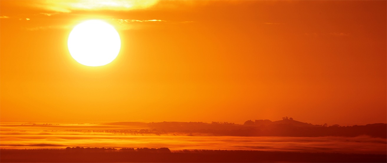 A photograph shows the sun low in the sky at sunset.