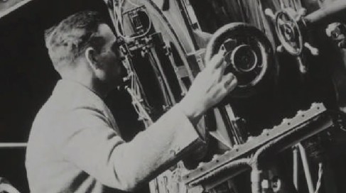 Photograph of Edwin Hubble, adjusting instrument settings as he peers through a finder-scope on the 100-inch telescope on Mt. Wilson.