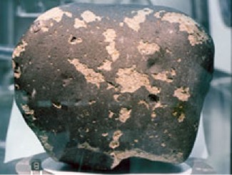 Image of a martian rock. This smooth, slightly pitted rock is nearly black with speckles of lighter colored material scattered over the surface.