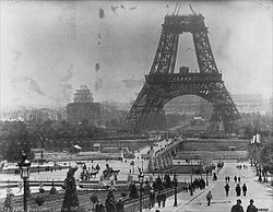 A black and white image showing the Eiffel Tower under construction.