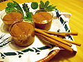 Chocolate mousse in cups on a platter with cinnamon sticks and greenery as garnish.