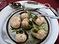 Escargot on a plate with special tongs and forks to use for eating. 