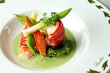 A dish with watercress, crayfish, and asparagus in a white bowl.