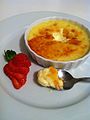A plate that has crème brûlée and strawberries on it. 