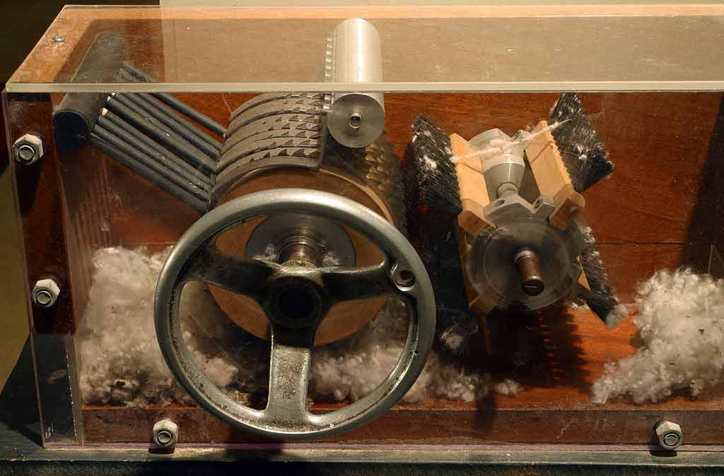 Photograph of nineteenth century cotton gin with cotton and both ends of the machine.