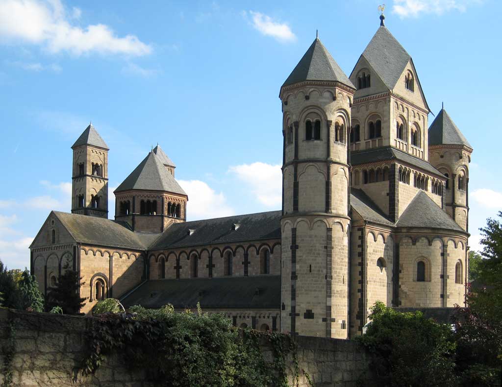 Picture of Maria Laach Abbey in Germany. From the outside, one sees three large towers that welcome visitors into the cathedral. A long nave follows with the chancel in the rear of the cathedral.