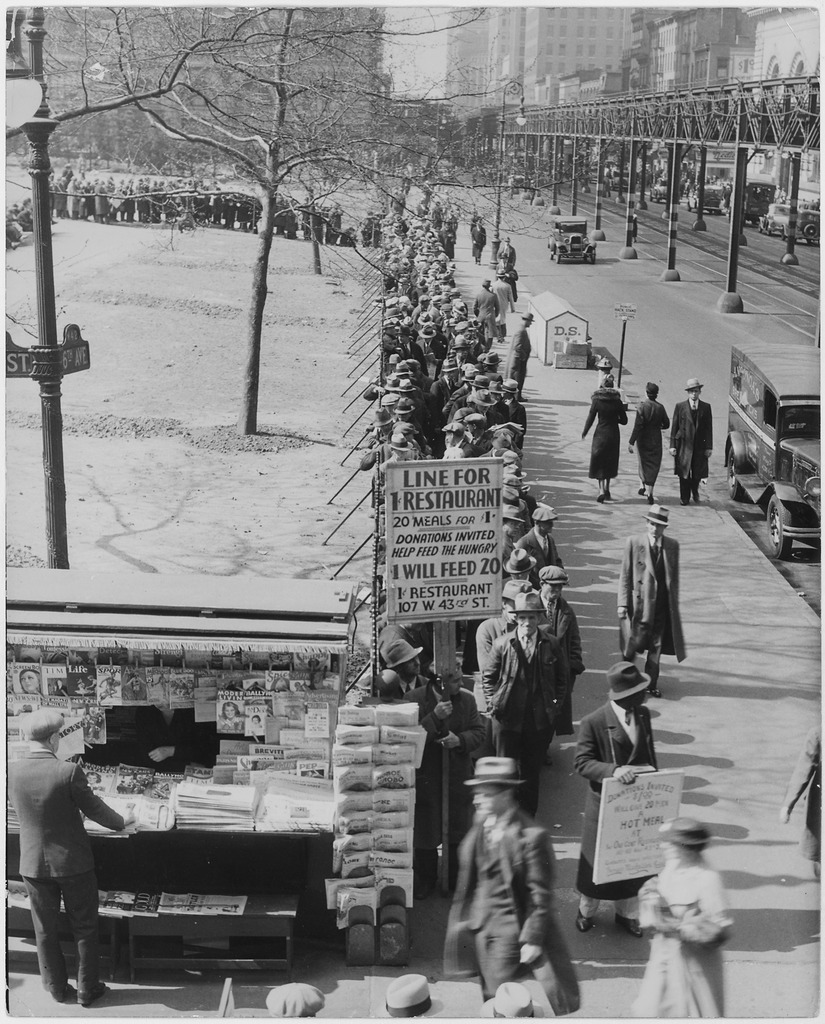 Black and white image of a bread line stretching around the corner of a city block. A large sign in the front reads: 'Line for 1 cent restaurant. Twenty meals for one dollar. Donations invited - help feed the hungry. One dollar will feed twenty.'