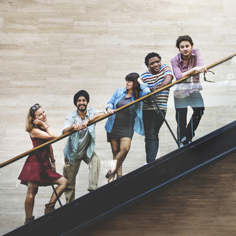 A group of young adult friends stand together on a staircase.