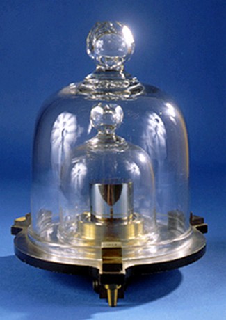The photo shows a small metal cylinder on a stand. The cylinder is covered with 2 glass lids, with the smaller glass lid encased within the larger glass lid.