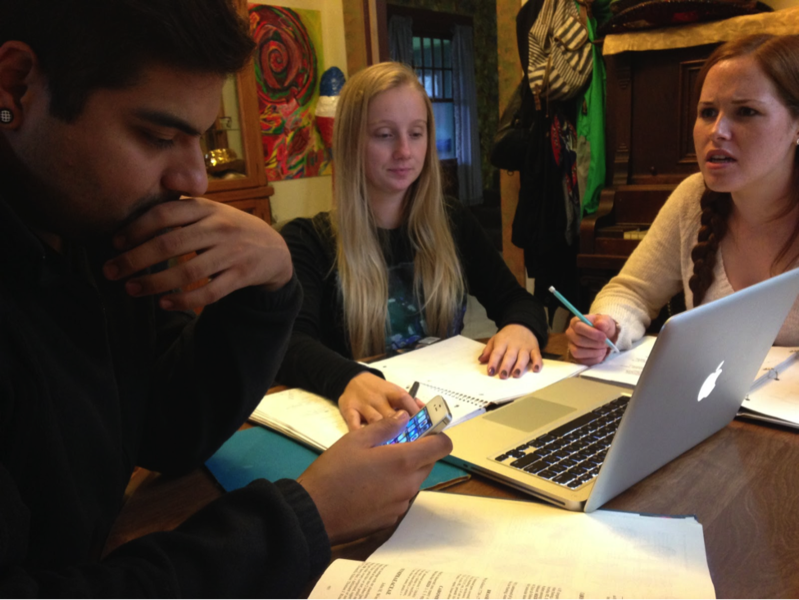 Photo of three students sitting at a table together, working on a project