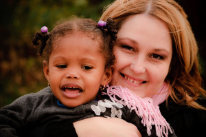 Photo of woman with caucasian features holding a little girl with African American features