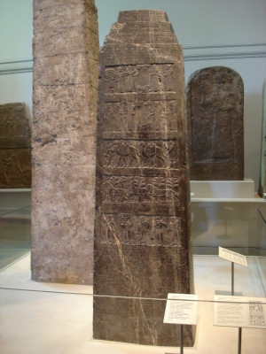 Photo of black limestone Assyrian sculpture with many scenes in bas-relief and inscriptions