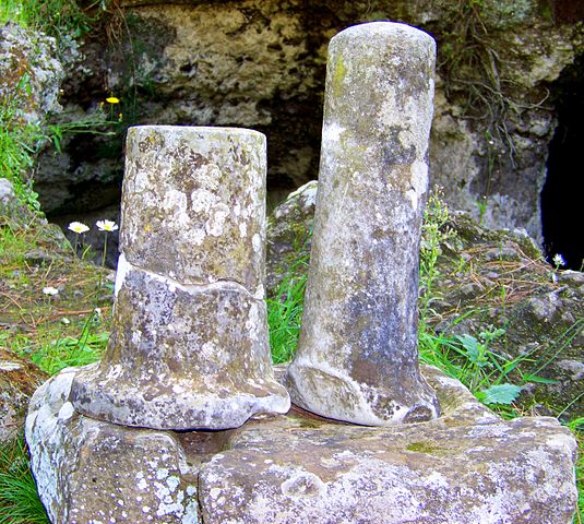 This is a photo of two short cylindrical columns (cippi) outside a tomb.