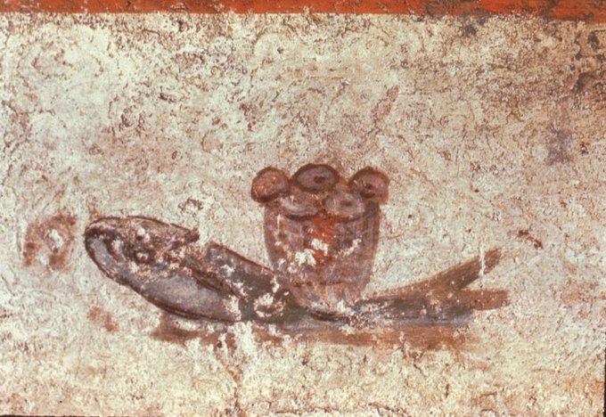 This is a photo of iconography from the Christian Catacombs. It depicts five loaves of bread and two fish, alluding to Jesus feeding the multitude.