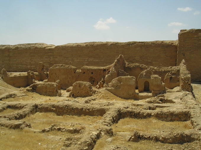 This is a photo of the remains of the Synagogue at Dura-Europos. It shows the ruins of the courtyard, western porch and prayer hall. The remains resemble a sand castle in color and shape.