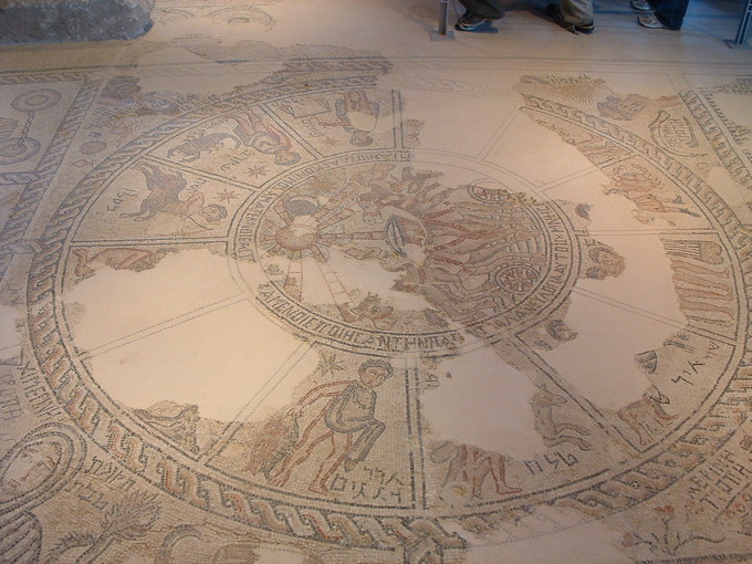 This is a photo of a mosaic on the floor at the Sepphoris synagogue. There is a large Zodiac with the names of the months written in Hebrew. Helios sits in the middle, in his sun chariot.