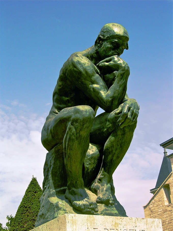 The work shows a nude male figure of over life-size sitting on a rock with his chin resting on one hand as though deep in thought.