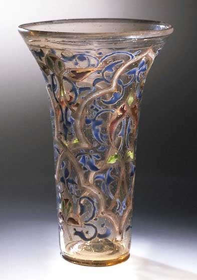 This is a photo of the glass beaker, The Luck of Edenhall. It is a glass elegantly decorated with arabesques in blue, green, red and white enamel with gilding