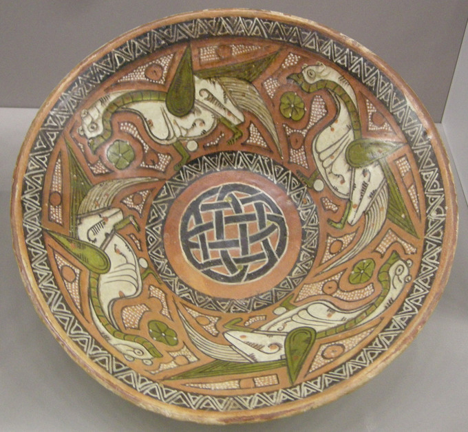 This photo shows a 10th century dish painted with complex geometric patterns and a repeated bird portrait. Islamic art has very notable achievements in ceramics, both in pottery and tiles for walls, which reached heights unmatched by other cultures. This dish is from East Persia or Central Asia.