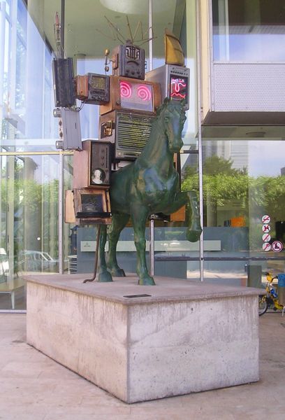 A boxy robot rides a green horse.