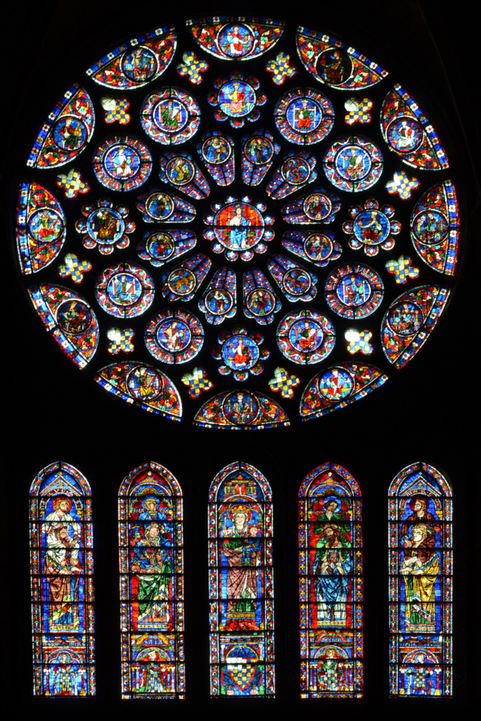 Image of south transept rose window, which is dedicated to Christ, who is shown in the center with his right hand raised, surrounded by angels. There are two outer rings of twelve circles each.