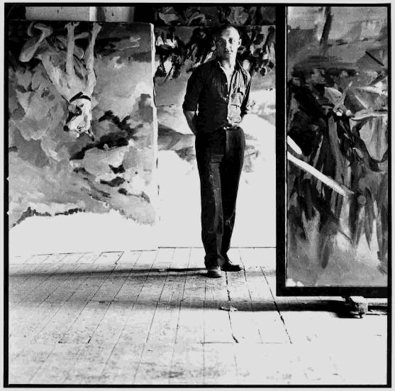A photo of Georg Baselitz standing amongst his art.