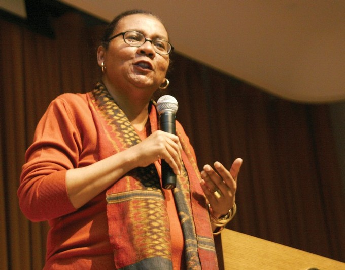A photo of bell hooks speaking into a microphone.