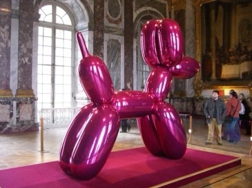 A picture of the giant, magenta balloon dog sculpture on display inside a museum.