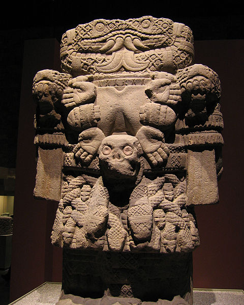 A boxy statue with a necklace made of hands and a skirt made of snakes.