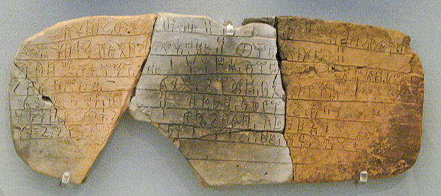 Photograph of a clay tablet broken into three pieces, covered with script.