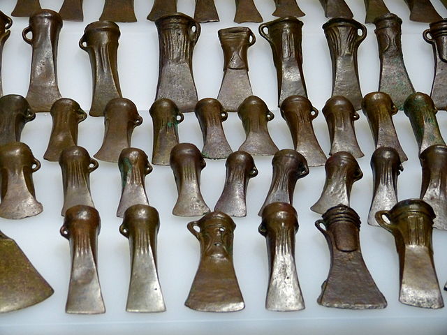 Photo depicts several bronze axe blades arranged in rows.