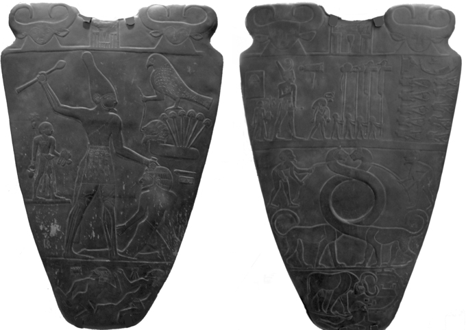 Photo that depicts front and back view of Narmer Palette, carved from soft dark gray-green siltstone. The scene on the front features large Narmer wielding a mace wearing a flower crown. On the left of the king is a man bearing the king's sandals. To the right of the king is a kneeling prisoner, who is about to be struck by the king. The scene on the back features a procession with King Narmer at the top. Below the procession, two men are holding ropes tied to the outstretched, intertwining necks of a mythical serpoard (serpent/leopard).