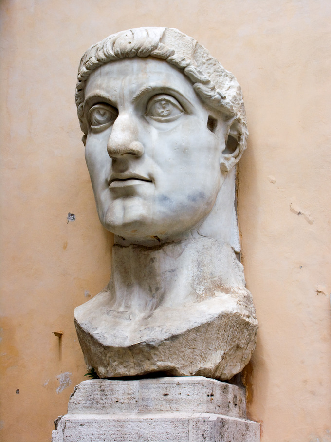Photo of the giant sculpture of the head of the colossus of Constantine, depicted with large wide eyes and a strong jawline.