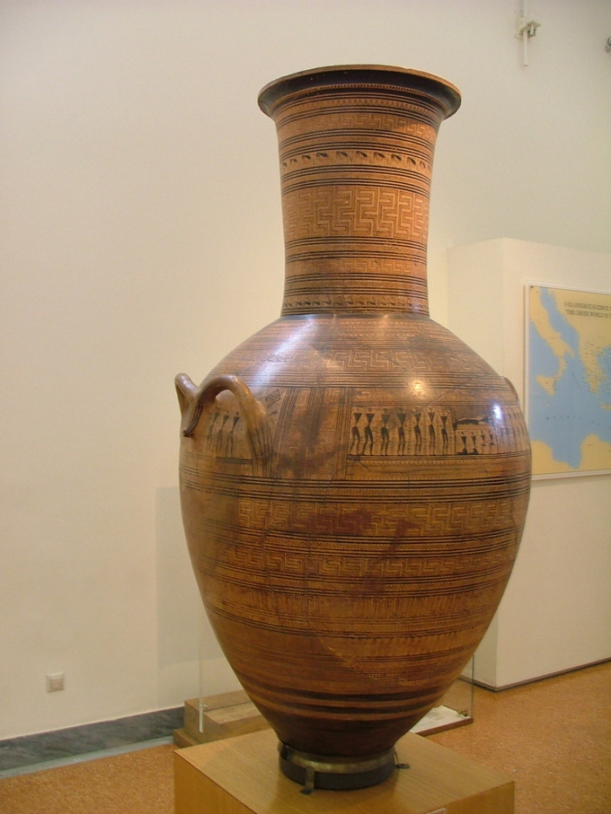Color photo shows a Greek amphora ( a tall jar with two handles and a narrow neck). It is decorated with a variety of geometric patterns.