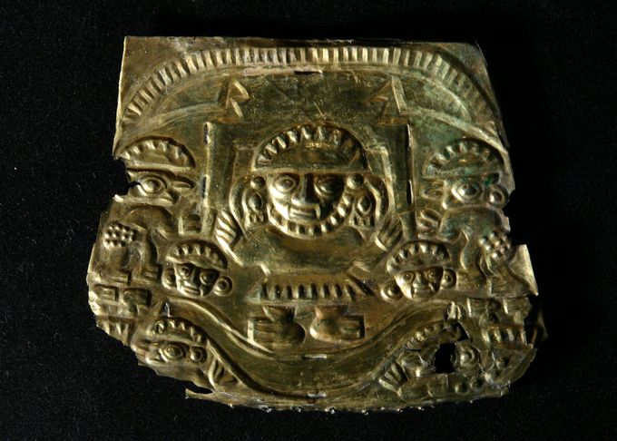 Metal plaque depicting a figure in the center with smaller figures on the edges.