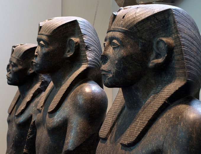 Sculpture of three pharaohs in profile view. All are shirtless and wearing head crowns.