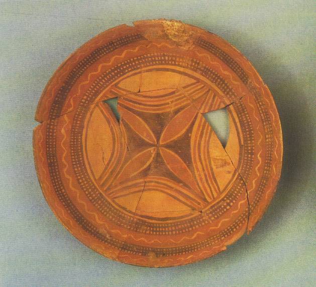 Photo depicts a flat, circular piece of pottery reconstructed from broken shards. Some of the pieces are missing.
