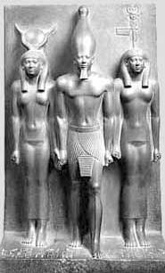 Sculpture depicts a frontal view three figures. A male figure in the middle wears tall cone-shaped headpiece. He wears only a loincloth. He is flanked by two nude female figures.