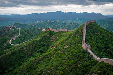 The wall is pictured winding through lush green hills into the distance.