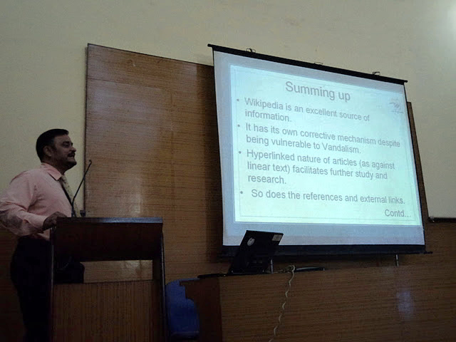 A picture of a speaker showing the last slide in a presentation during the Wiki Conference in India.