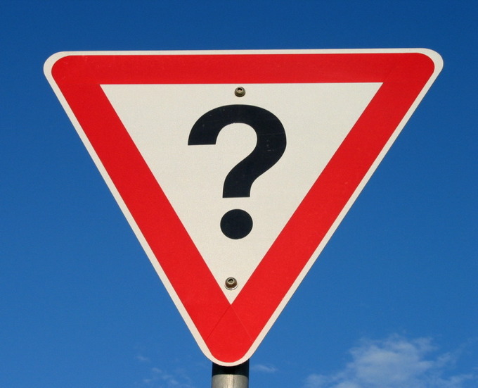A picture of a triangular street sign with a question mark on it.